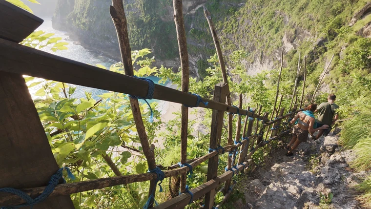 第三次 · 精灵海滩下崖路段：贴着木扶手沿陡峭碎石台阶往下走。